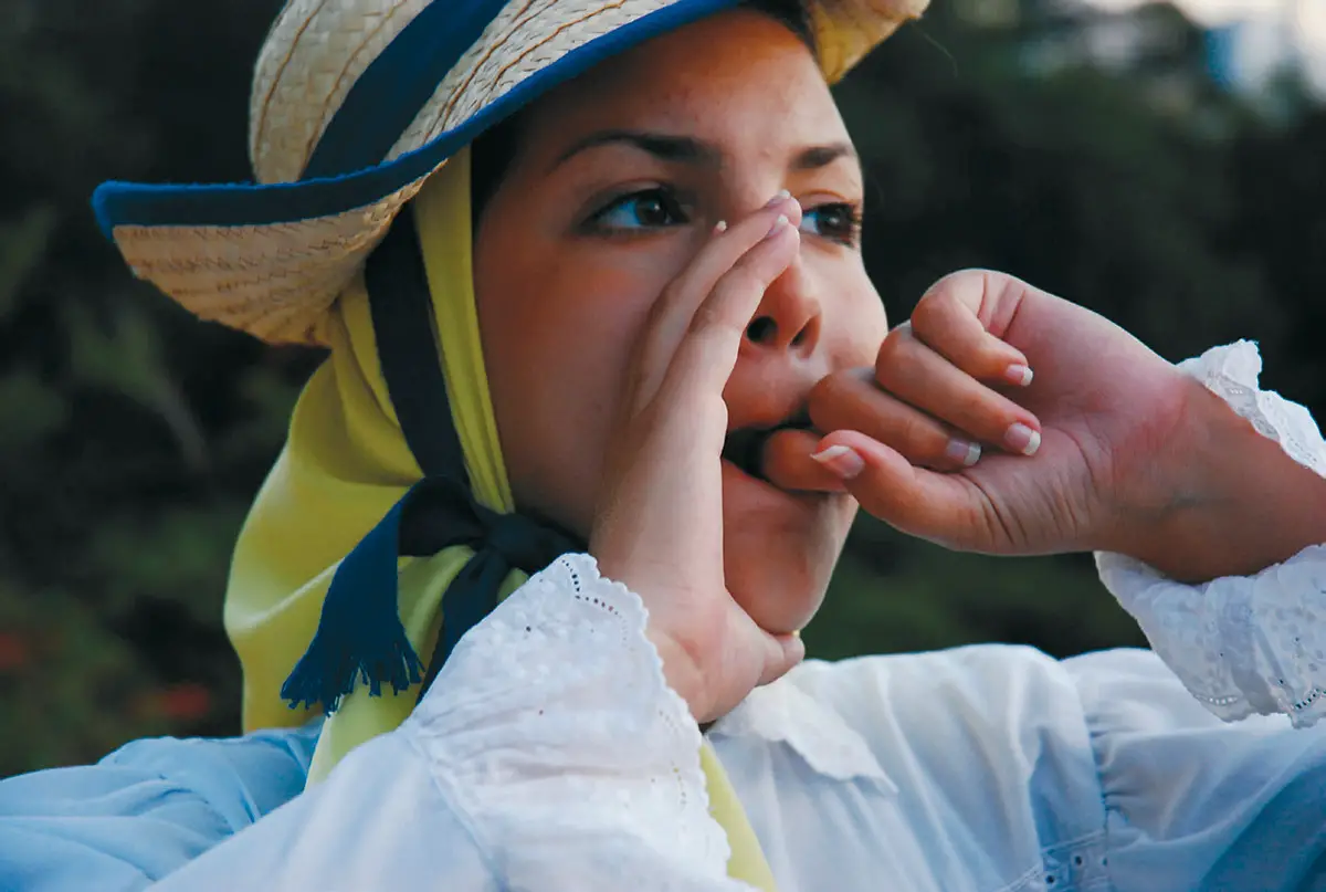 Mujer con traje tradicional de La Gomera practicando el Silbo Gomero, patrimonio cultural de Canarias