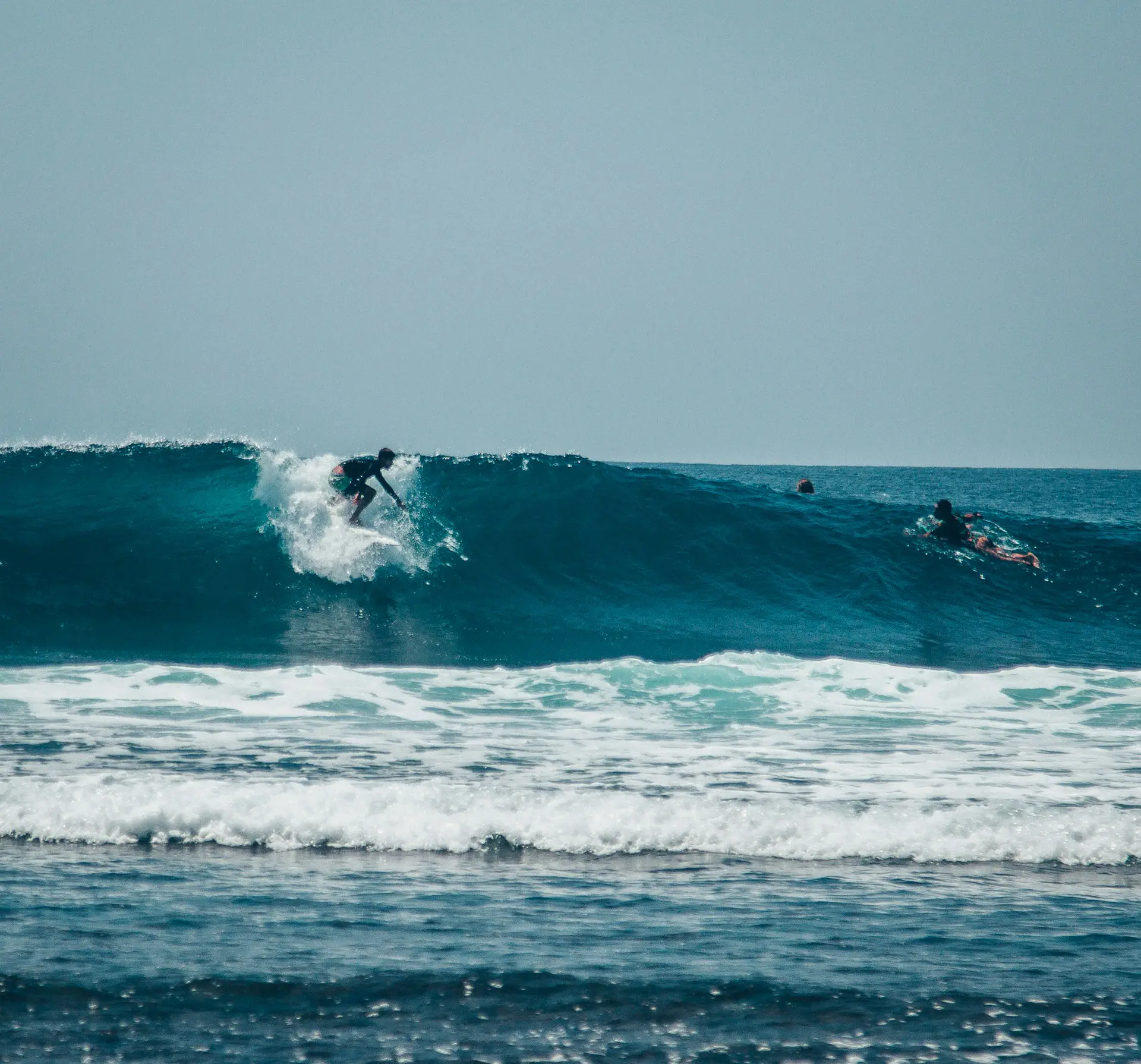Personas surfeando una ola como portada para la actividad de surf de Canarian Scene.