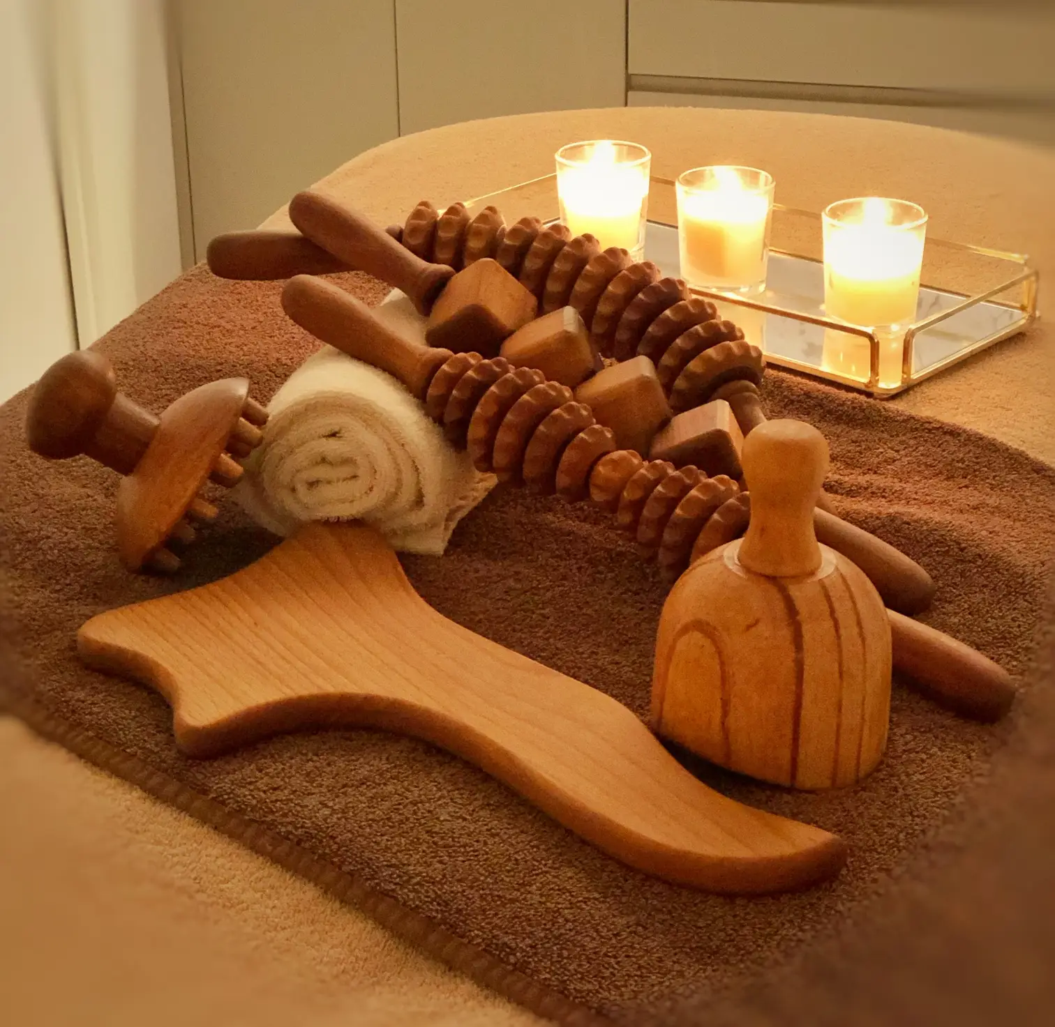 Herramientas para terapia de maderotrapia sobre mesa y tres velas encendidas.
