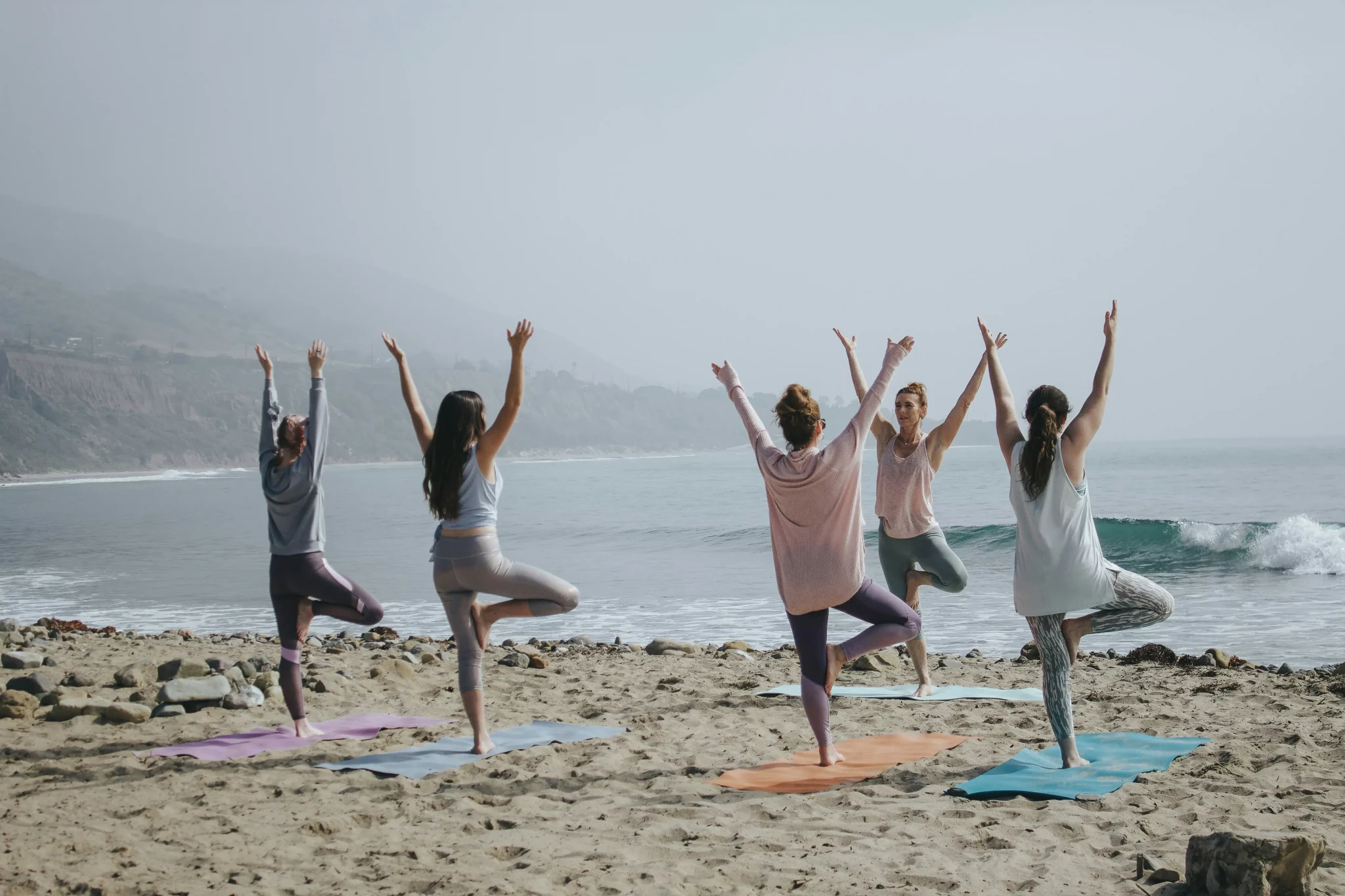 Grupo de personas practicando el yoga en la playa.