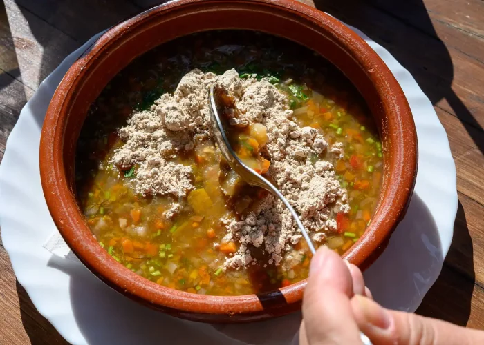 Potaje en cuenco de barro con gofio espolvoreado por encima.