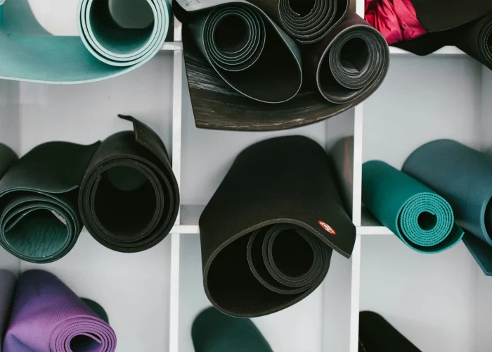 Varias esterillas de yoga colocadas en diferentes huecos de una estantería blanca.