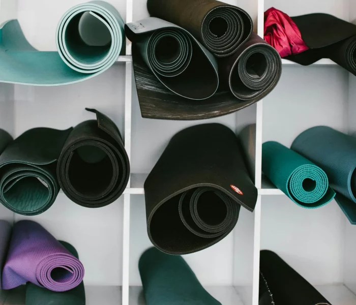 Varias esterillas de yoga colocadas en diferentes huecos de una estantería blanca.